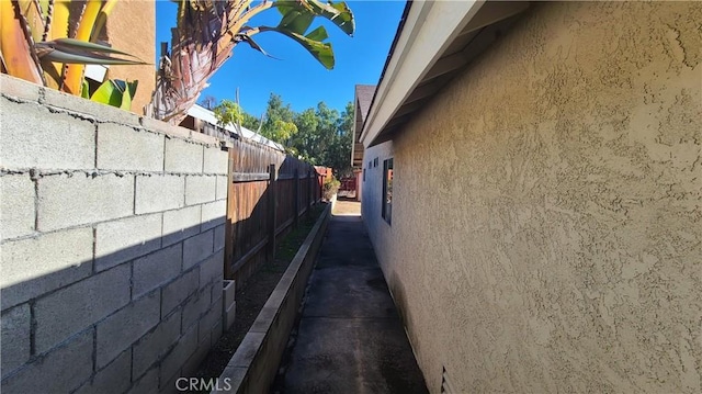 view of side of property with stucco siding and fence