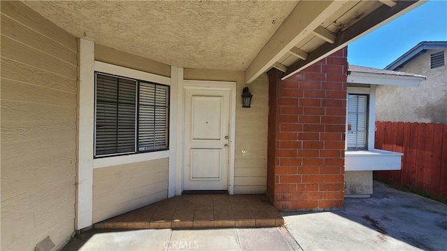 property entrance with stucco siding and fence