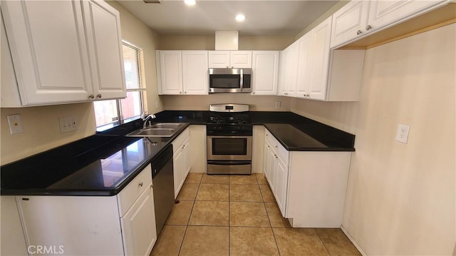 kitchen featuring dark countertops, white cabinets, stainless steel appliances, and a sink