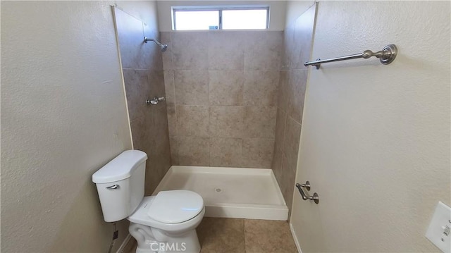 bathroom with tile patterned floors, toilet, and tiled shower