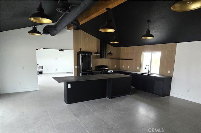 kitchen with dark countertops, a center island, range with gas cooktop, hanging light fixtures, and a sink