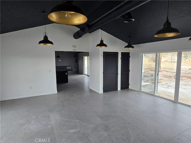 spare room featuring lofted ceiling with beams, plenty of natural light, and baseboards