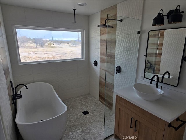 bathroom featuring a walk in shower, vanity, and a freestanding tub