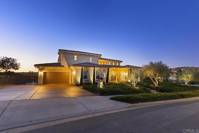 mediterranean / spanish house with stucco siding, driveway, an attached garage, and a tiled roof