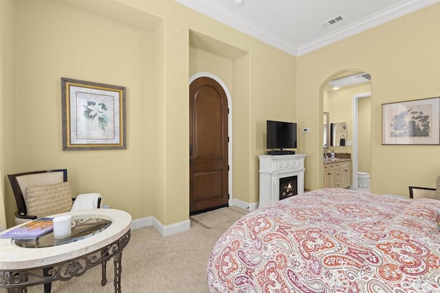 bedroom with visible vents, light carpet, arched walkways, crown molding, and baseboards