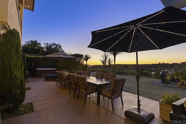 patio terrace at dusk featuring outdoor dining space and a hot tub