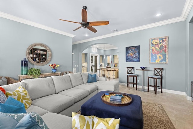 living room with crown molding, baseboards, light tile patterned flooring, arched walkways, and a ceiling fan