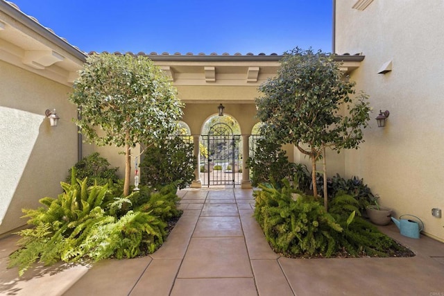 entrance to property with stucco siding and a gate