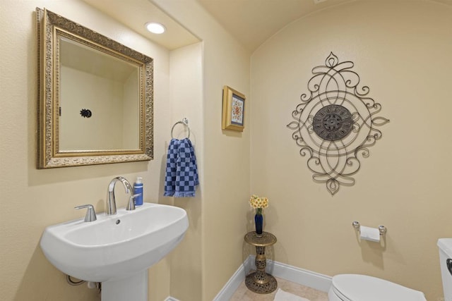 bathroom featuring tile patterned flooring, toilet, baseboards, and a sink