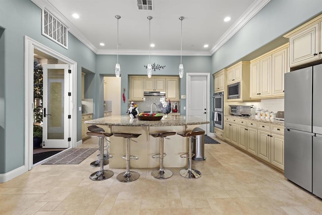 kitchen with under cabinet range hood, visible vents, cream cabinetry, and appliances with stainless steel finishes