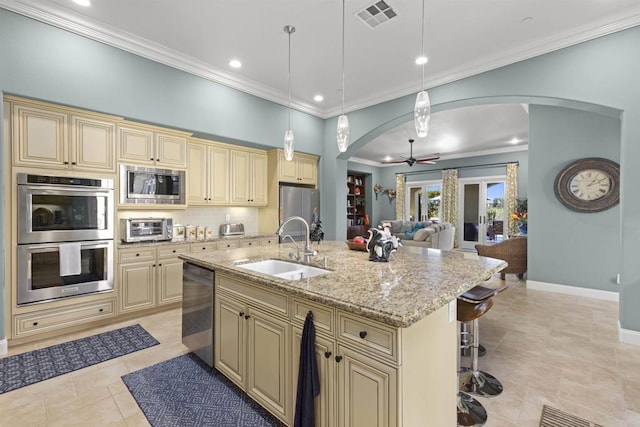 kitchen with visible vents, arched walkways, cream cabinetry, and appliances with stainless steel finishes