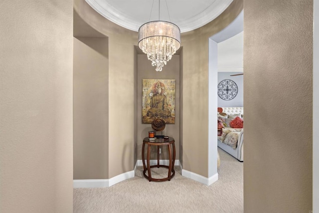 hallway featuring crown molding, baseboards, a chandelier, carpet flooring, and a textured wall