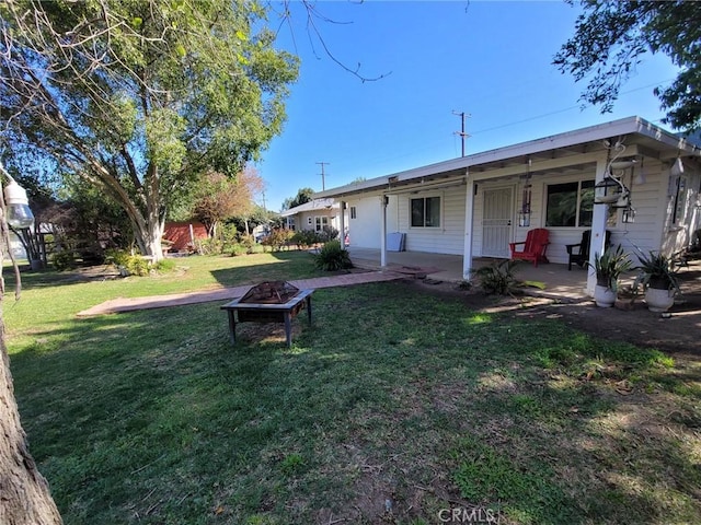 rear view of property with a yard and a fire pit