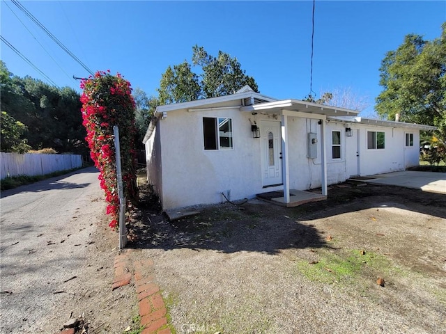 bungalow featuring fence and stucco siding