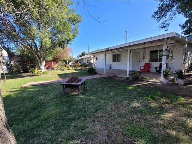 rear view of house featuring a fire pit and a lawn