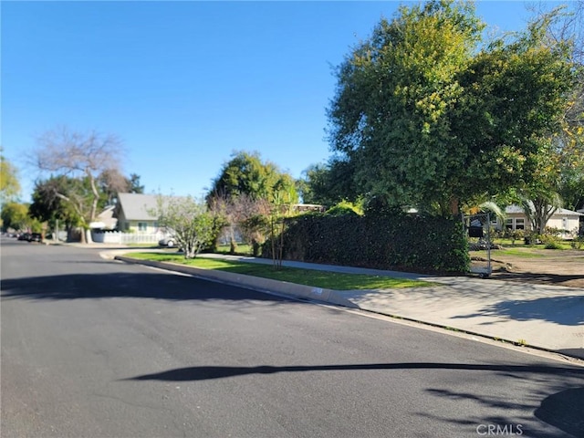 view of road with a residential view, curbs, and sidewalks