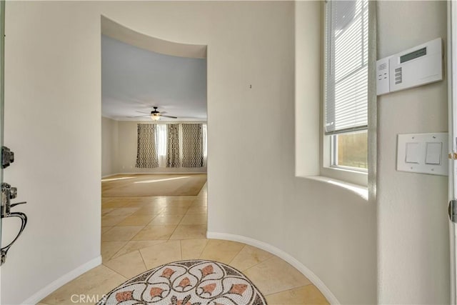 hall featuring light tile patterned floors and baseboards