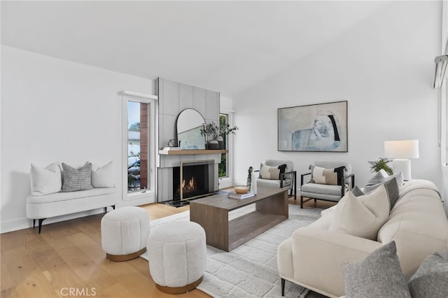 living room featuring lofted ceiling, light wood-style flooring, and a fireplace