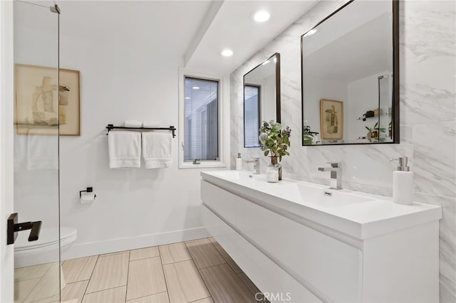 bathroom with a sink, baseboards, toilet, and double vanity