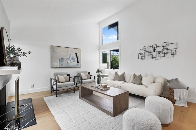 living room with a high ceiling, baseboards, and wood finished floors