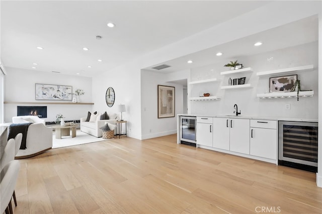 living room with wine cooler, wet bar, and light wood finished floors