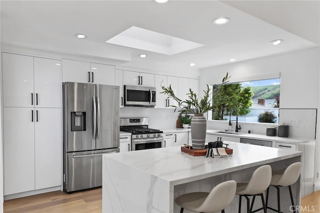 kitchen featuring modern cabinets, a sink, stainless steel appliances, a breakfast bar area, and a skylight