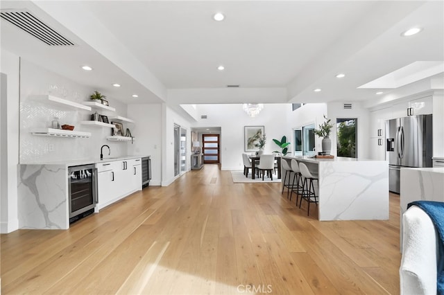 kitchen featuring visible vents, beverage cooler, stainless steel refrigerator with ice dispenser, open shelves, and white cabinets