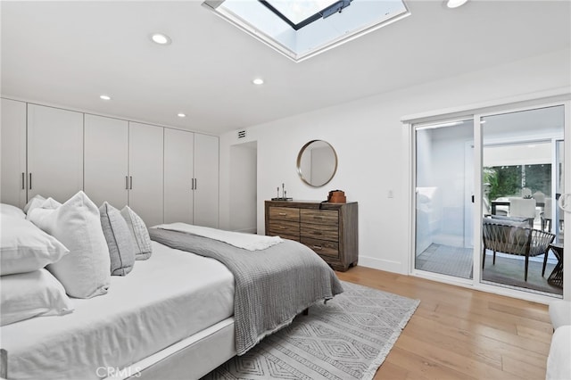 bedroom featuring recessed lighting, light wood-style flooring, a skylight, and access to outside