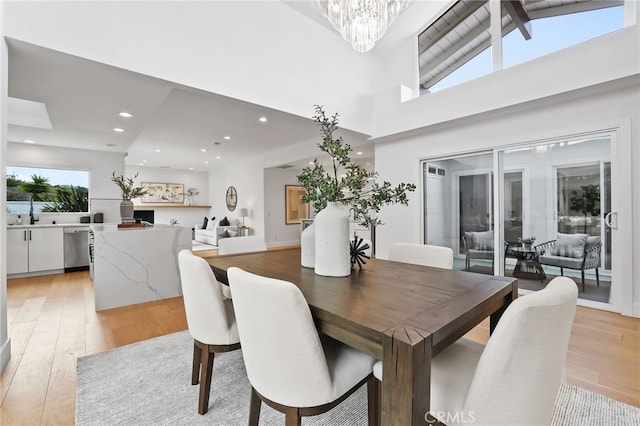 dining room featuring a notable chandelier, recessed lighting, high vaulted ceiling, and light wood-style floors