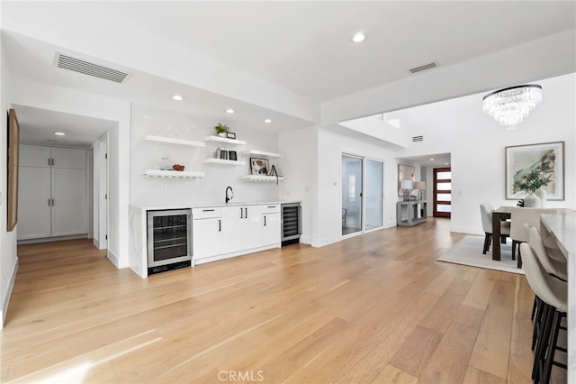 interior space featuring indoor wet bar, wine cooler, visible vents, and light wood finished floors