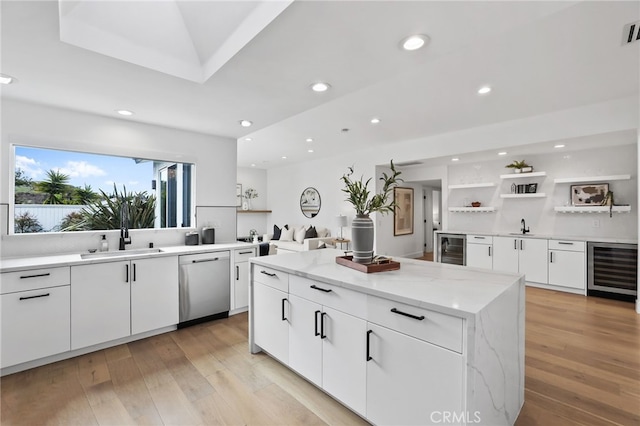 kitchen with beverage cooler, open shelves, a sink, stainless steel dishwasher, and a center island