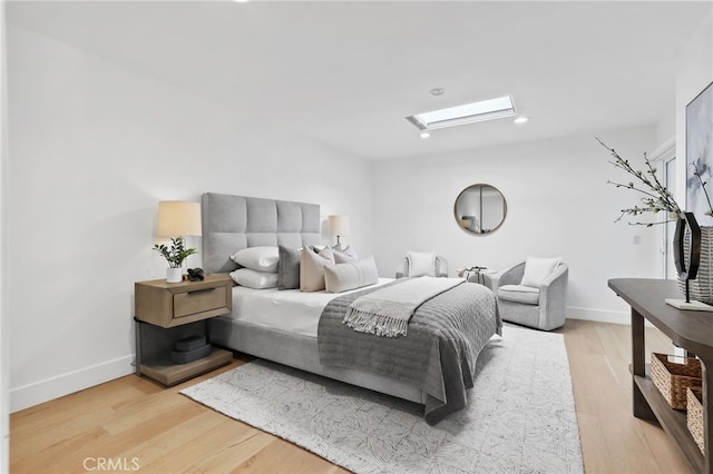 bedroom with light wood-style flooring, a skylight, and baseboards