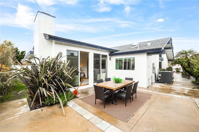 back of property with stucco siding, central air condition unit, outdoor dining area, and a patio area