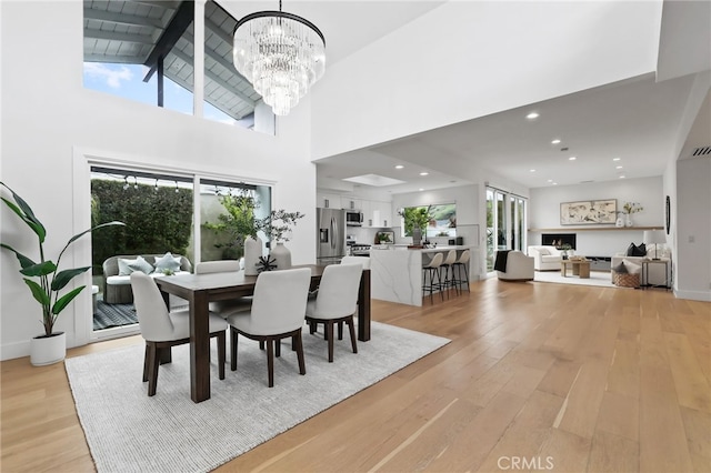 dining room featuring light wood finished floors, a notable chandelier, beamed ceiling, and high vaulted ceiling