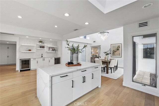 kitchen with visible vents, beverage cooler, open shelves, white cabinetry, and light wood finished floors