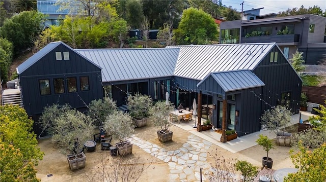 rear view of property featuring a patio area, board and batten siding, metal roof, and a standing seam roof