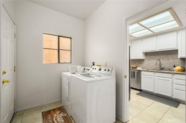 laundry area featuring washer and clothes dryer, a sink, cabinet space, light tile patterned floors, and baseboards