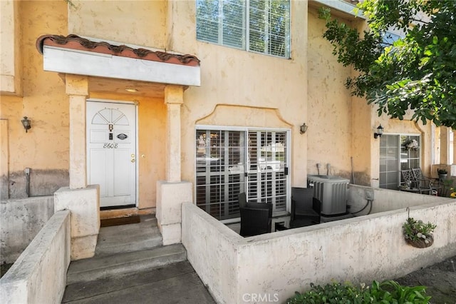 doorway to property featuring cooling unit and stucco siding