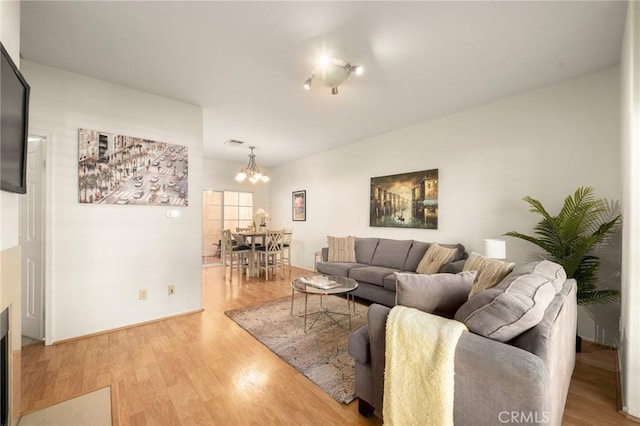 living area with light wood finished floors and a notable chandelier