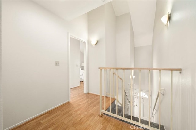 corridor with an upstairs landing, baseboards, and wood finished floors