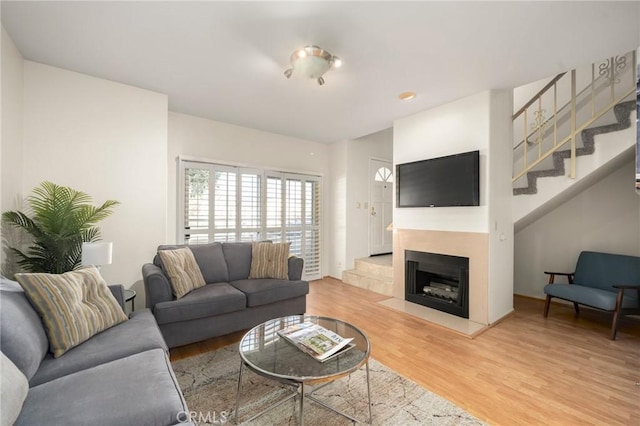 living area with stairs, light wood-style flooring, and a fireplace