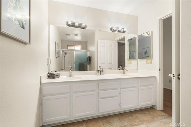 bathroom with double vanity, a stall shower, and a sink