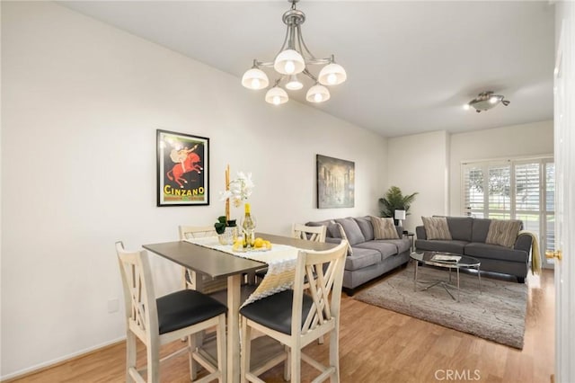 dining room featuring an inviting chandelier, baseboards, and light wood finished floors