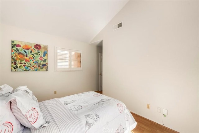 bedroom featuring visible vents, wood finished floors, and vaulted ceiling