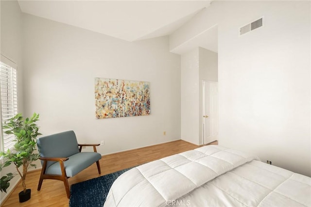 bedroom with visible vents, lofted ceiling, and wood finished floors