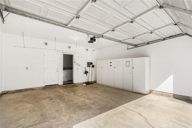 garage featuring washing machine and dryer, a garage door opener, and baseboards