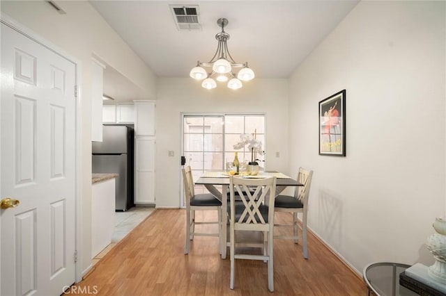 dining room with visible vents, baseboards, light wood-type flooring, and an inviting chandelier