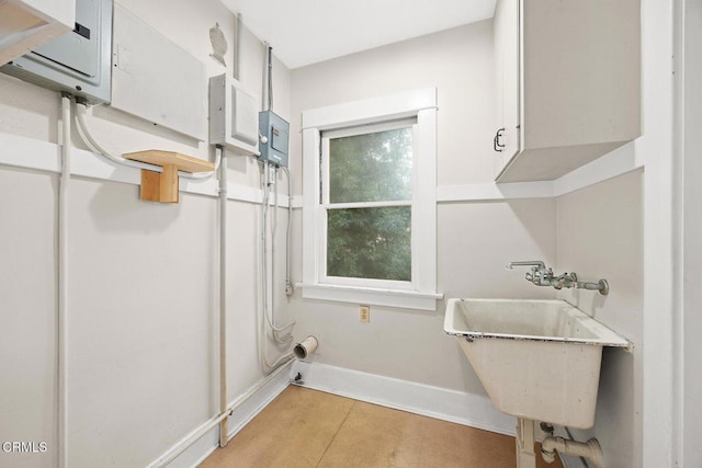 laundry room with cabinet space, baseboards, and a sink