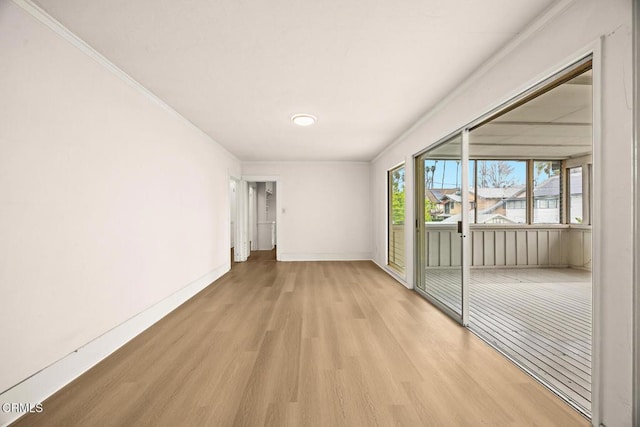 empty room with crown molding, wood finished floors, and baseboards