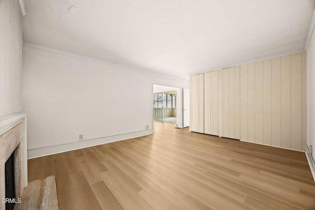 unfurnished living room featuring a fireplace, wood finished floors, and ornamental molding